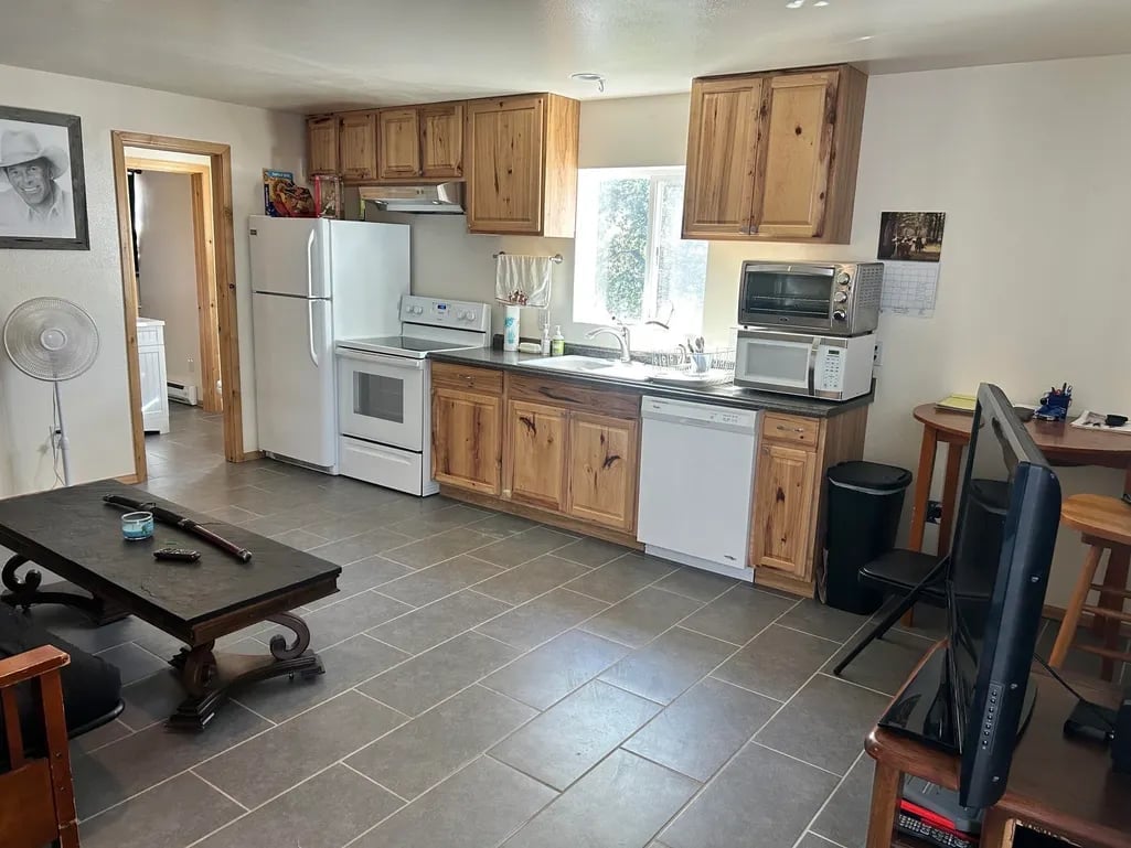 Open kitchen with wooden cabinets, white appliances, tile flooring, and casual seating area with pool table
